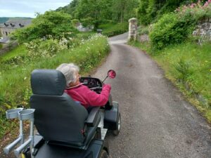 Lady in Tramper explores the grounds of National Trust Cotehele riding alone a tarmac path