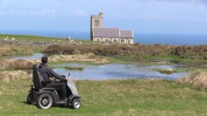 Man in tramper exploring Lundy Island. You can see a church and some sheep.