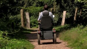 View of back of a man sat in a tramper on a path surrounded by trees at National Trust Fyne court
