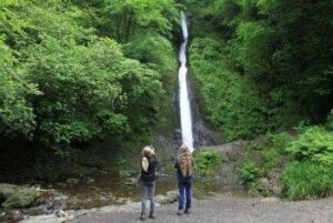 Two young girls looking at the waterfall at National Trust Lydford Gorge.
