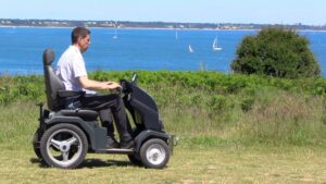 Sideview of man in tramper at National Trust Studland. Behind the man (behind him from the side view) is the sea, containing a number of sail boats. Coast can be seen in the distance.