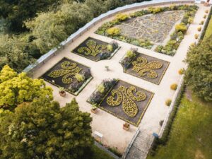 Aerial view of the gardens at the American Museums & Gardens. There are four plant beds, each with plants making a fleur de lis.