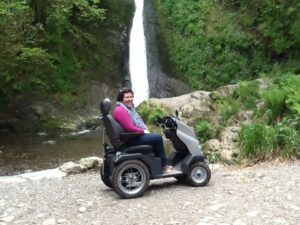 A lady in front of a waterfall in a tramper at Lydford Gorge smiling at the camera