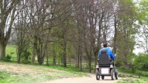 Man explores the path at Robinswood Hill Country Park form a Tramper. A wooden fence runs along the tree lined path