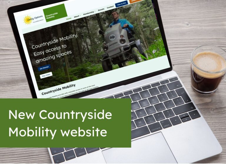 An open laptop with the Countryside Mobility homepage on screen. A coffee is on the table.
