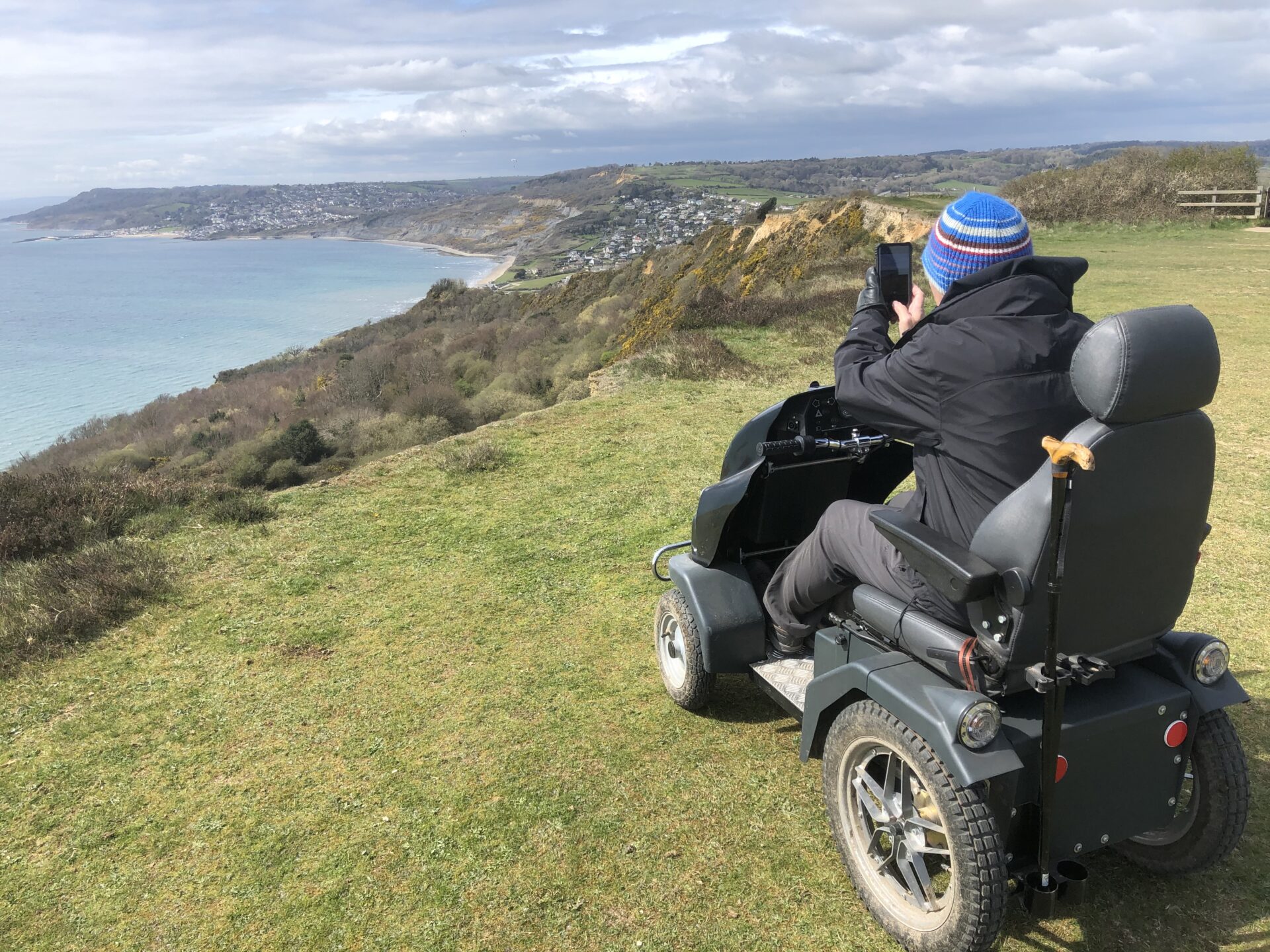 A visitor using an all terrain mobility scooter looks west along the Jurassic Coast towards Lyme Regis