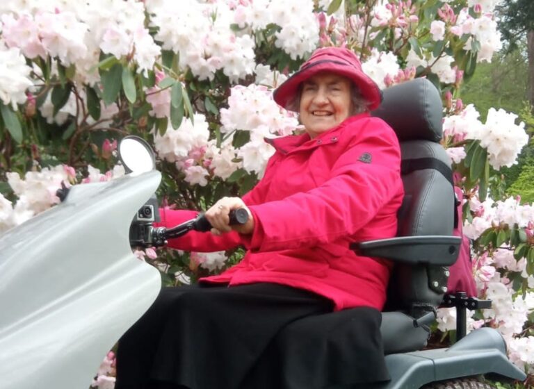 Liz Hartt drives a Tramper in front of blooming flowers
