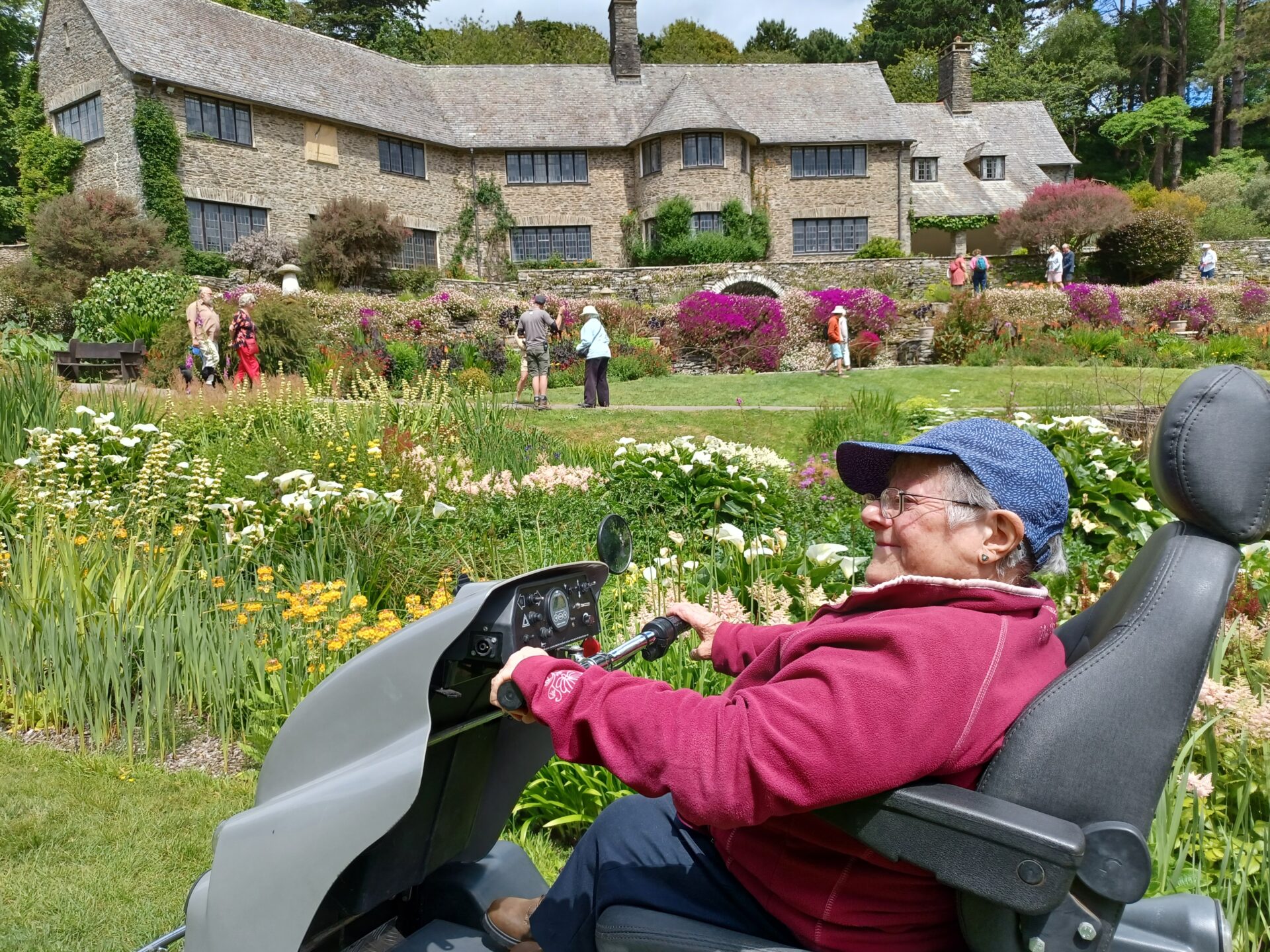 Visitor in mobility scooter (Tramper) in front of the 1920s house at Coleton Fishacre