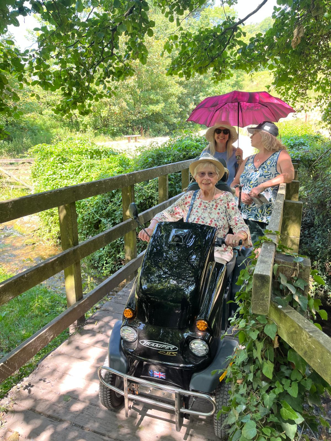 Eve smiling with her family while using the Tramper over a bridge. Her family is holding a parasol.